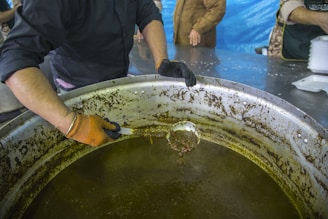 A Haitian artisan carefully stirring a pot of kremas, capturing the tradition behind each batch.