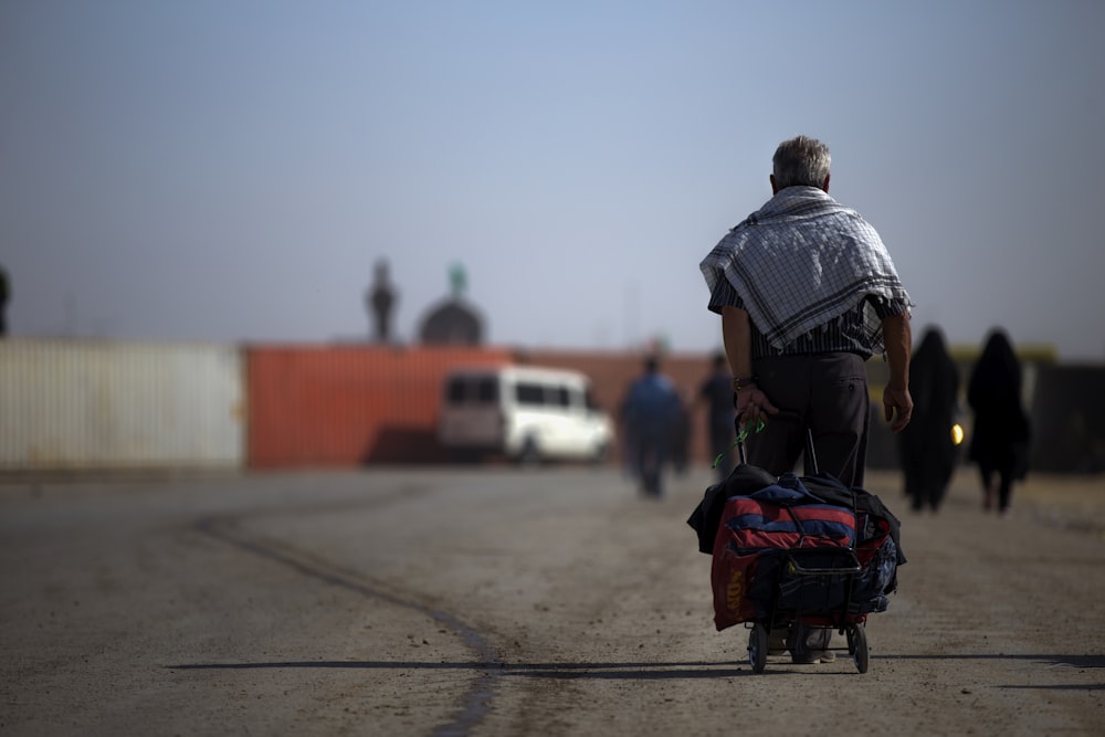 man walking while pulling wheeled bag