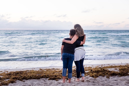 two woman standing on seashore near sea