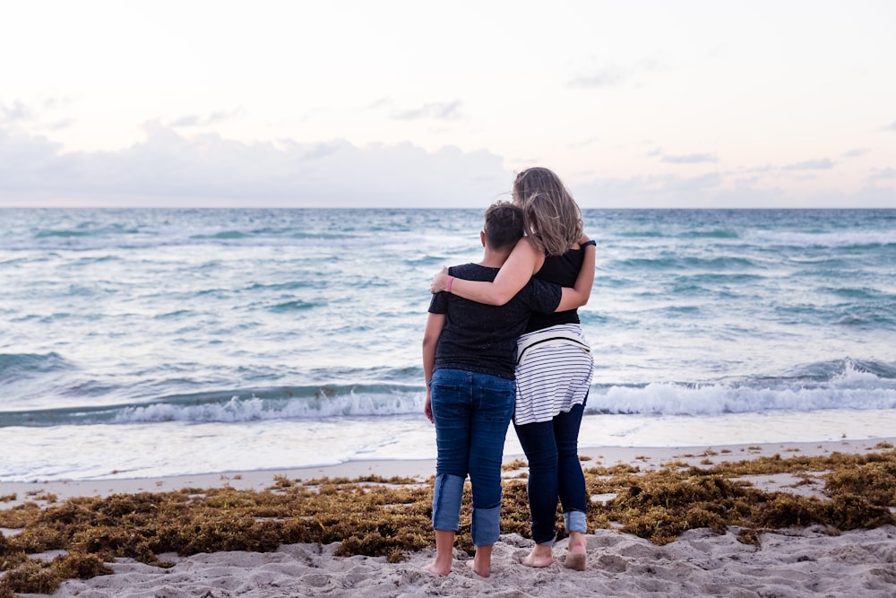 two woman standing on seashore near sea