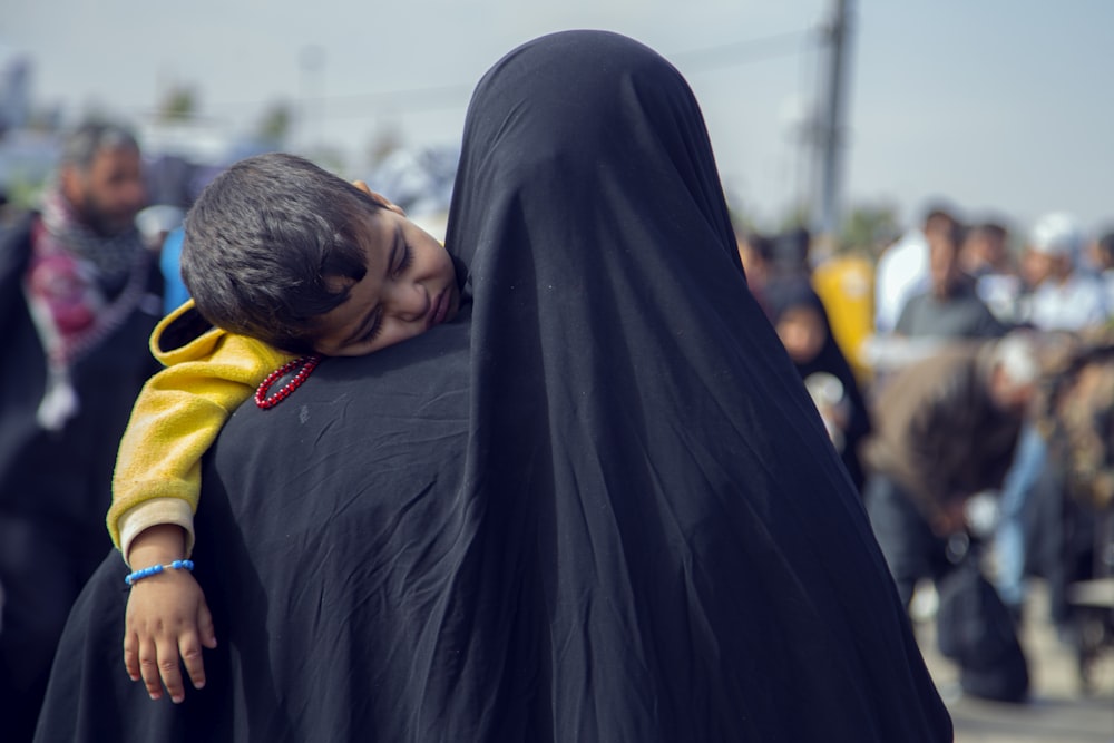 a woman in a black shawl hugging a child