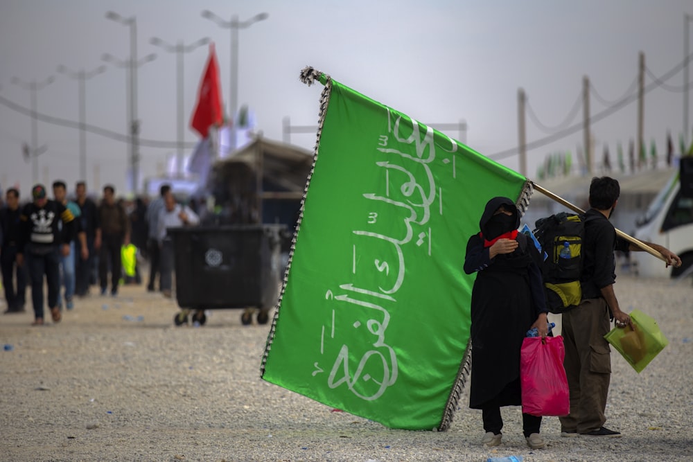 man and woman carrying green flag