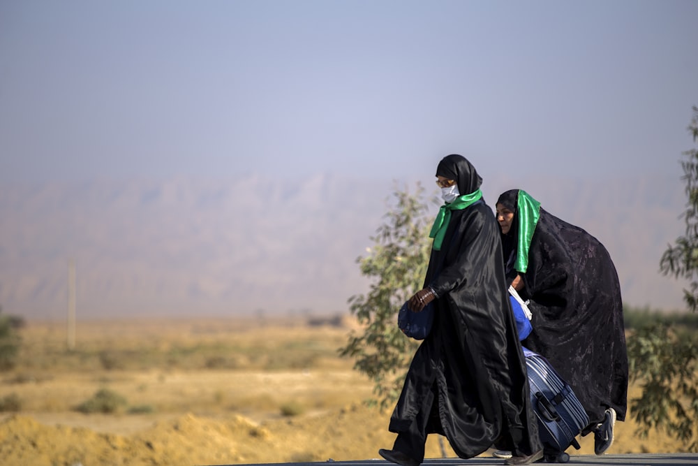 two person wearing black robes and green scarves