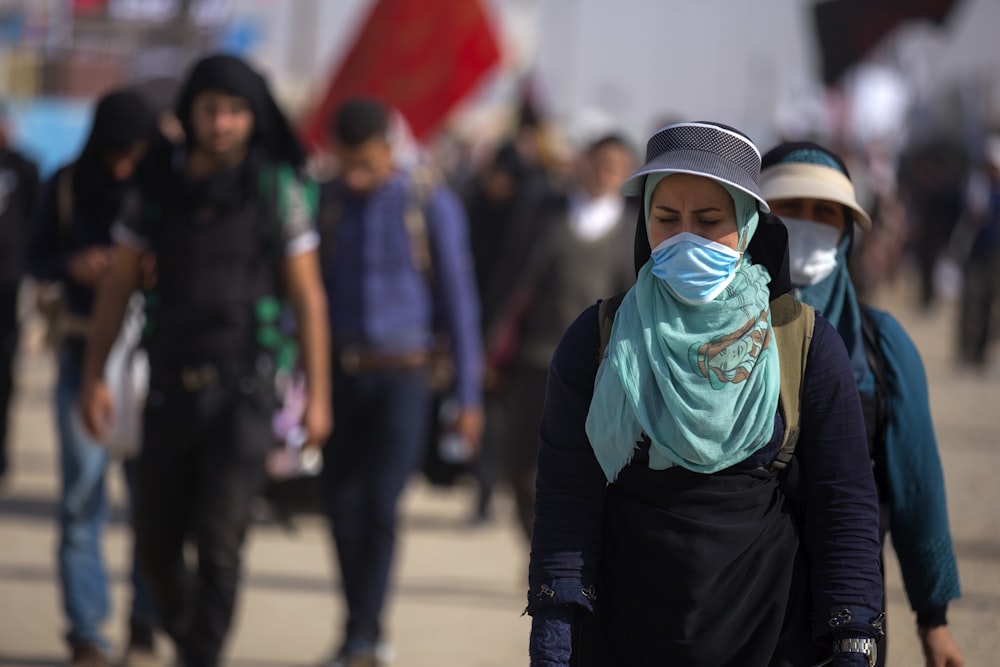 selective focus photography of woman walking in front of people during daytime