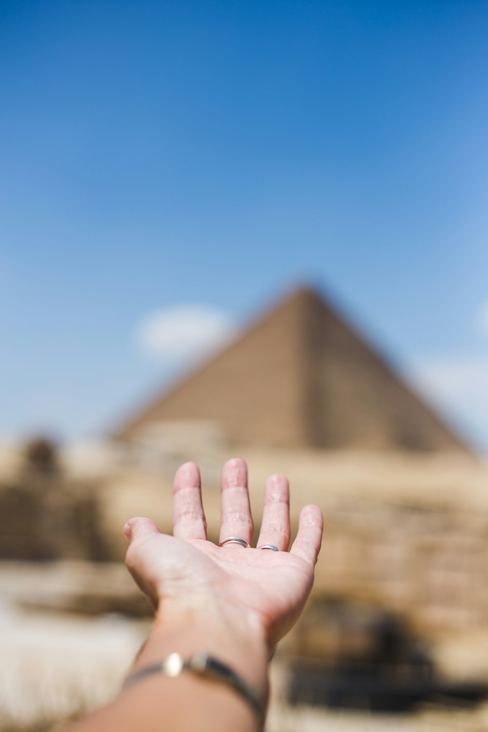 a person's hand reaching out towards a pyramid