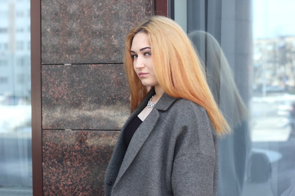 Femme en veste de costume grise près d’un mur de verre