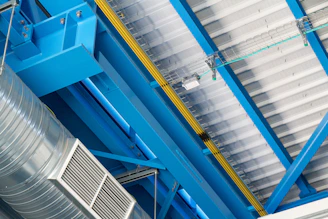 a blue and yellow structure with a large metal object hanging from it's side