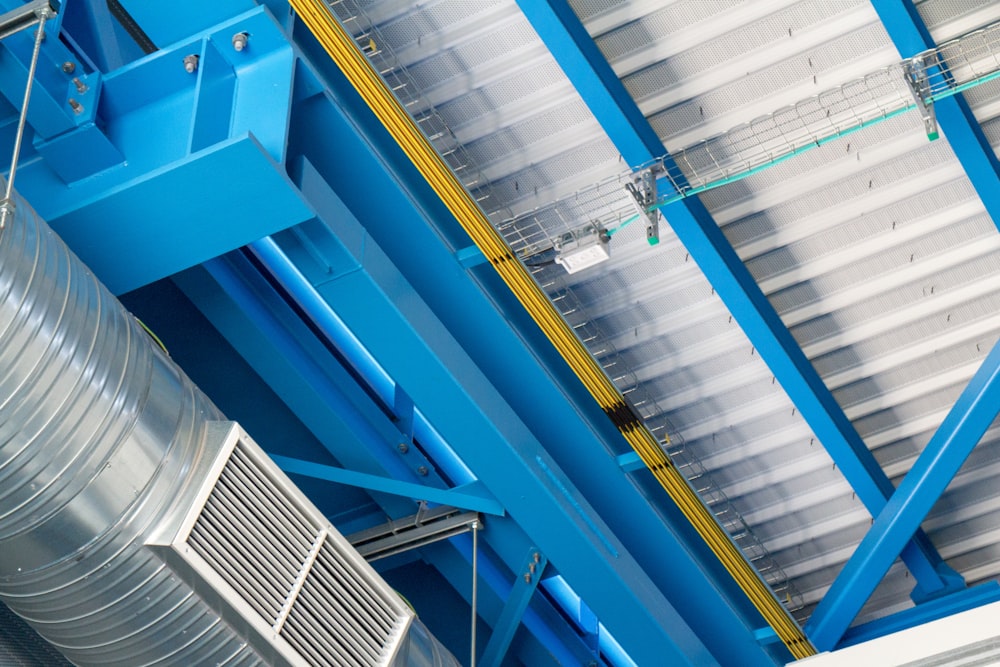 a blue and yellow structure with a large metal object hanging from it's side