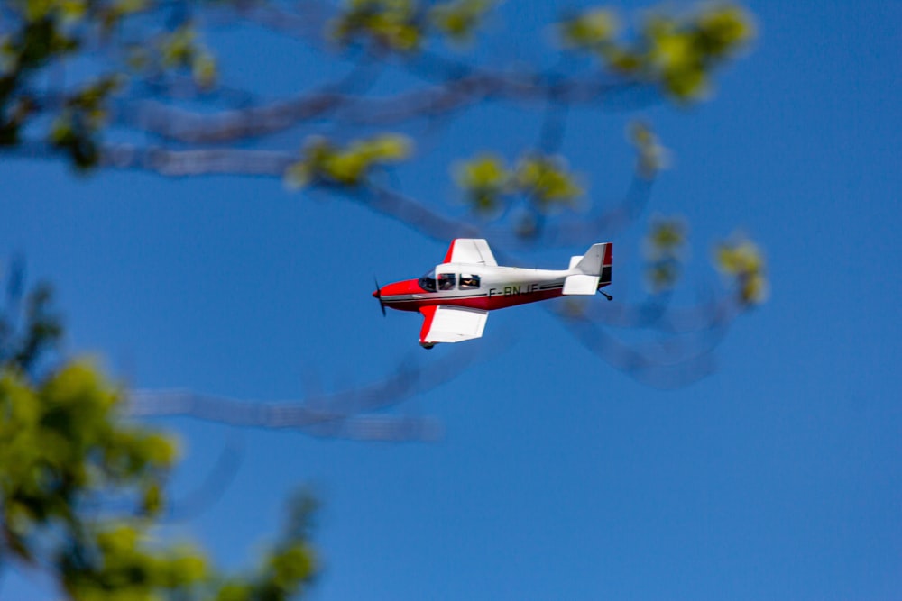 日中の飛行中の白と赤の複葉機の写真撮影