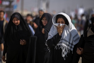 A serene gathering of family members in traditional Islamic attire offering support during a funeral.