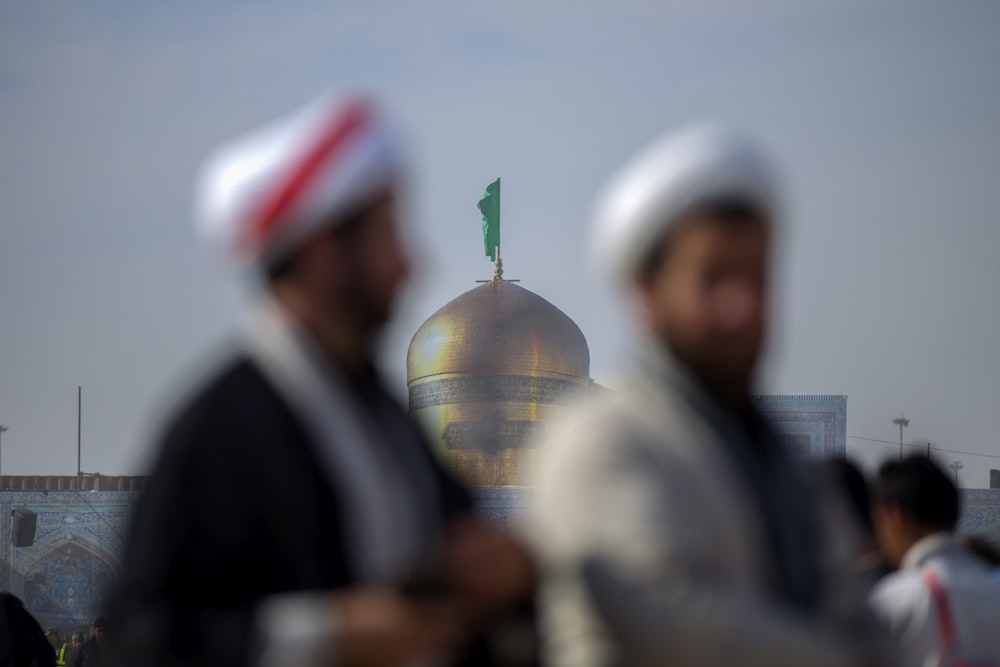 blurry photo of two men with mosque background