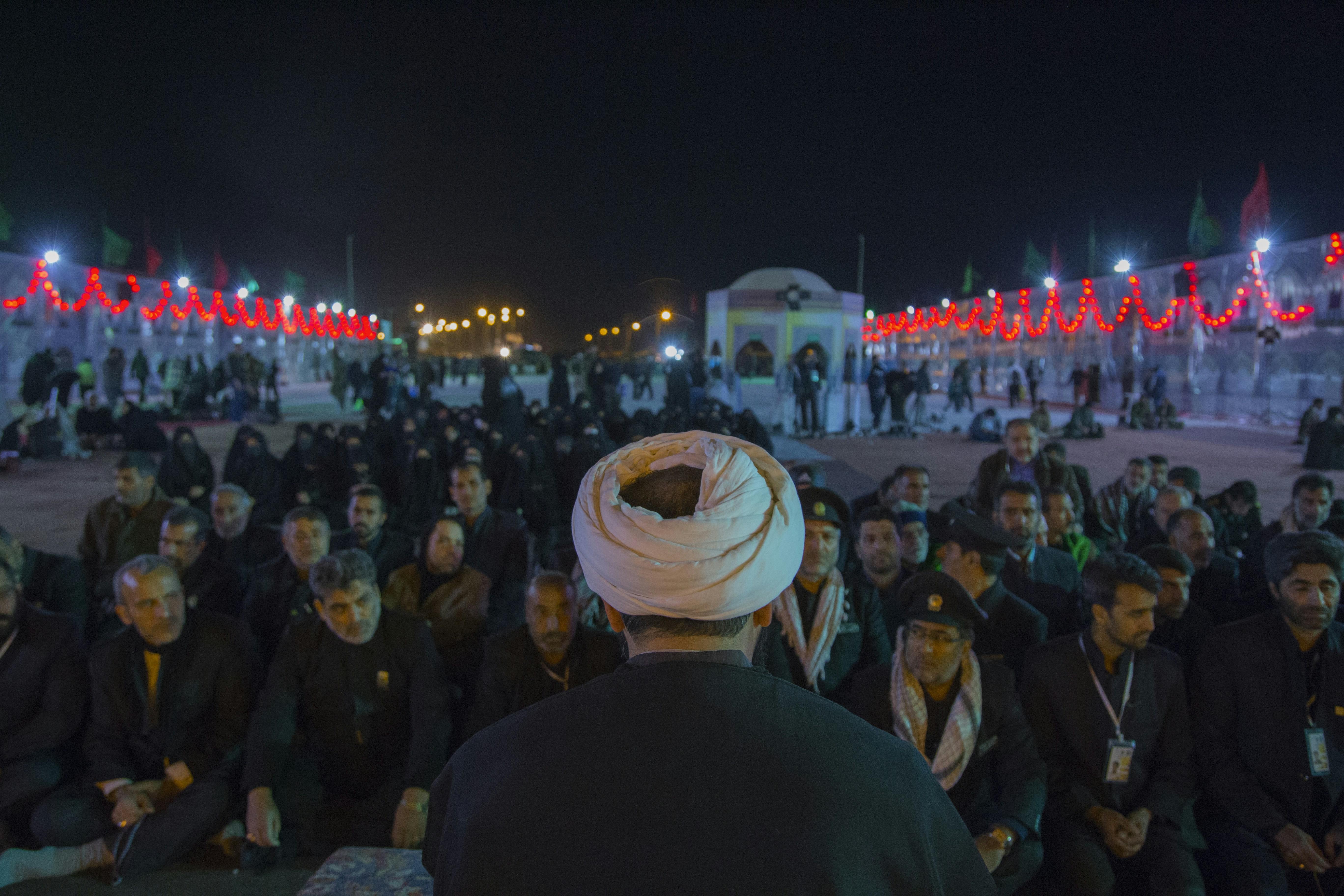 man standing in front of group of men sitting on ground iranian teams background
