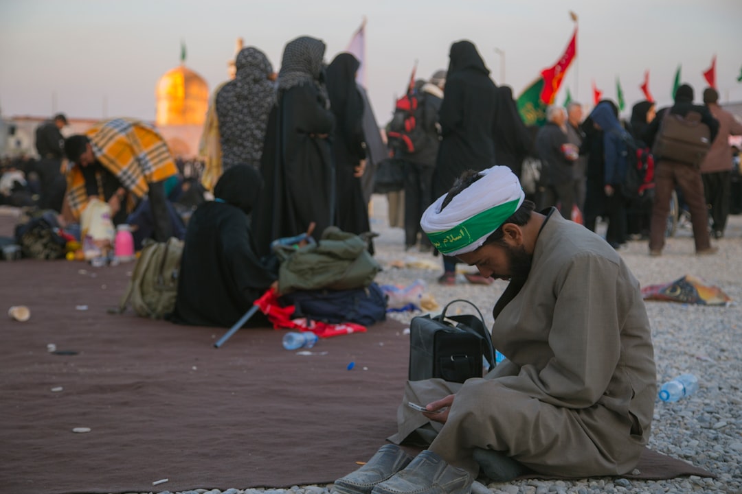 man sitting on ground wearing gray thobe dress