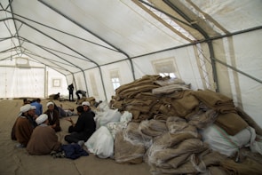 Volunteers warmly handing out food and pamphlets to smiling attendees under a bright tent.
