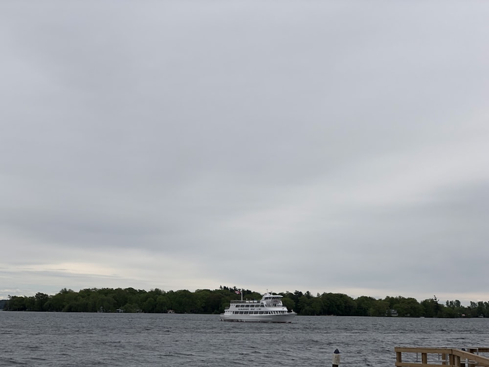 white yacht on body of water during cloudy day