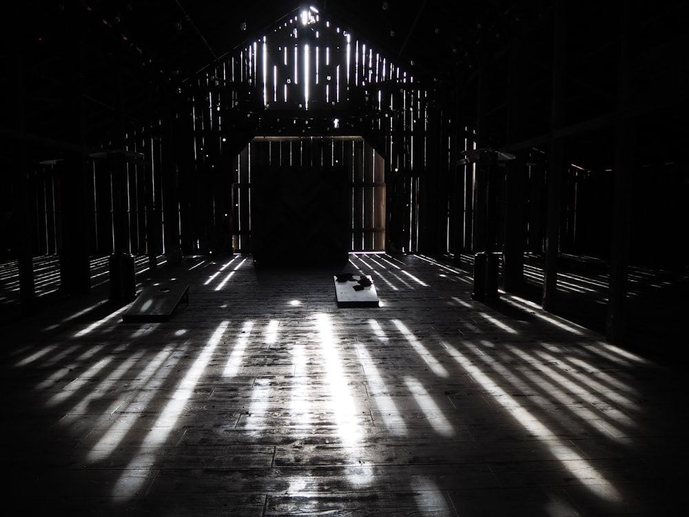 a dark barn with the sun shining through the windows