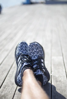 A close-up of a stylish, comfortable sandal resting on a sunlit wooden deck.