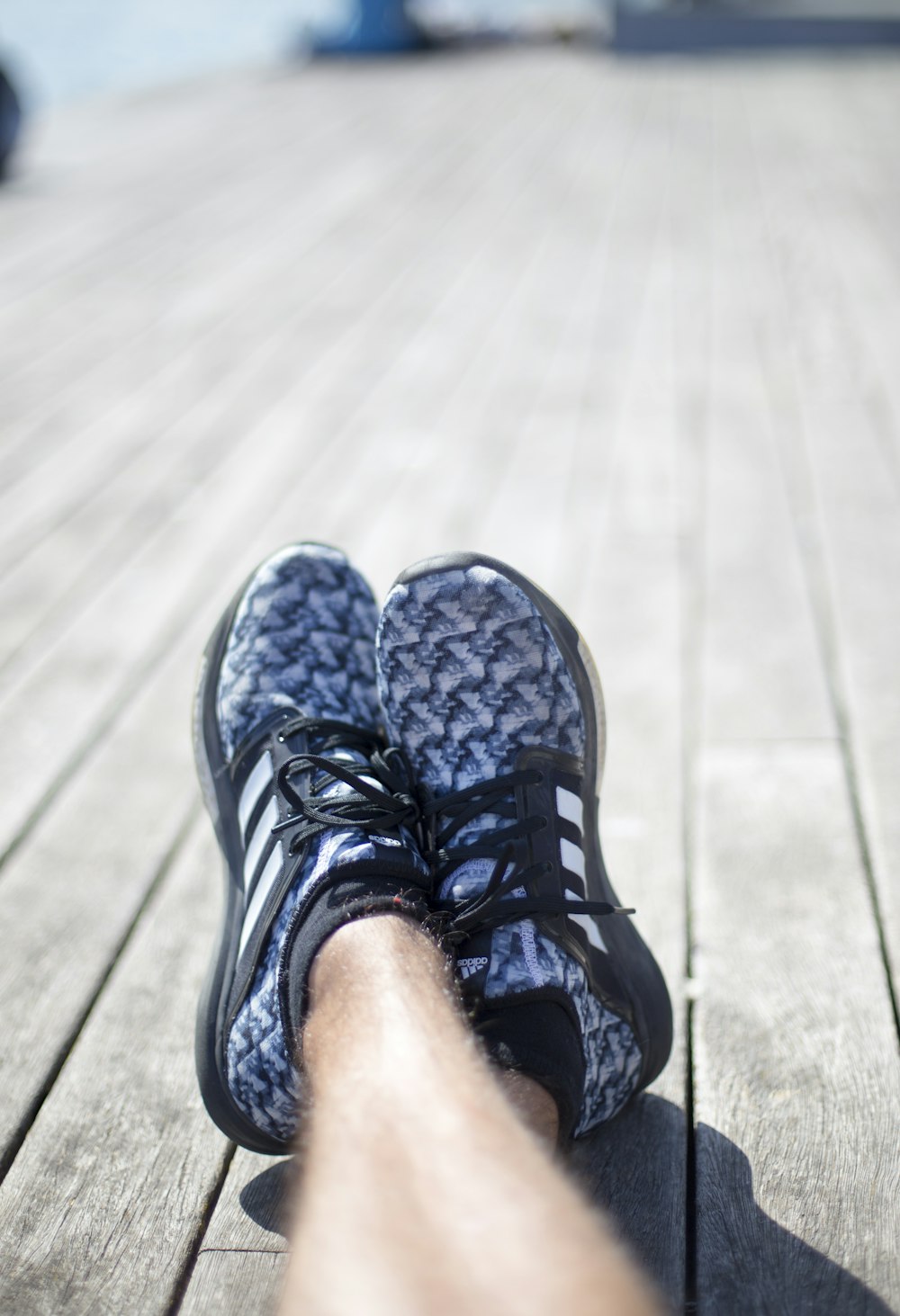 person wearing pair of blue-and-black adidas shoes