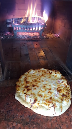 A warm, inviting photo of a wood-fired pizza next to a colorful display of cakes and drinks.