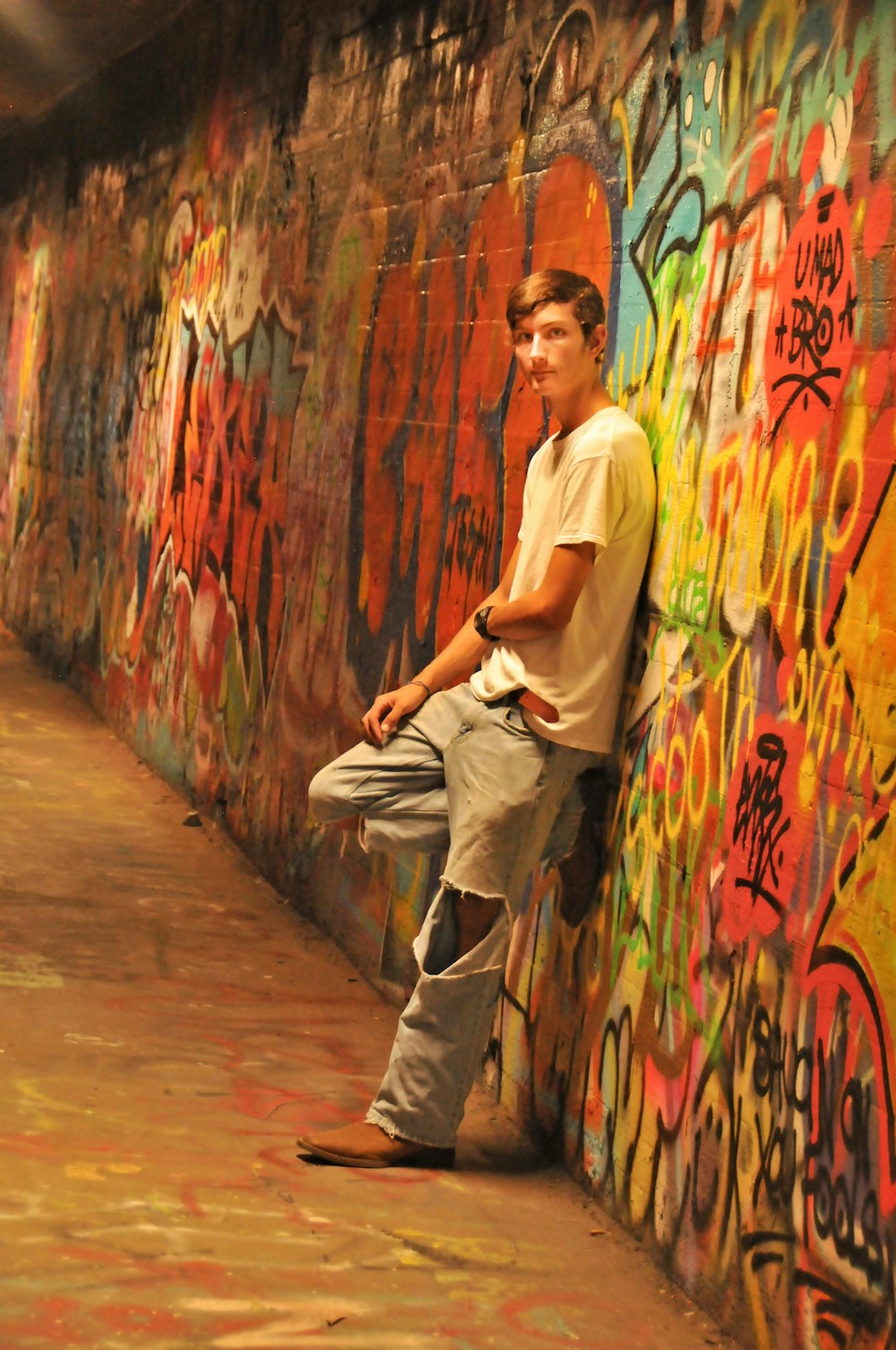 man looking at his left leaning backwards on wall with mural