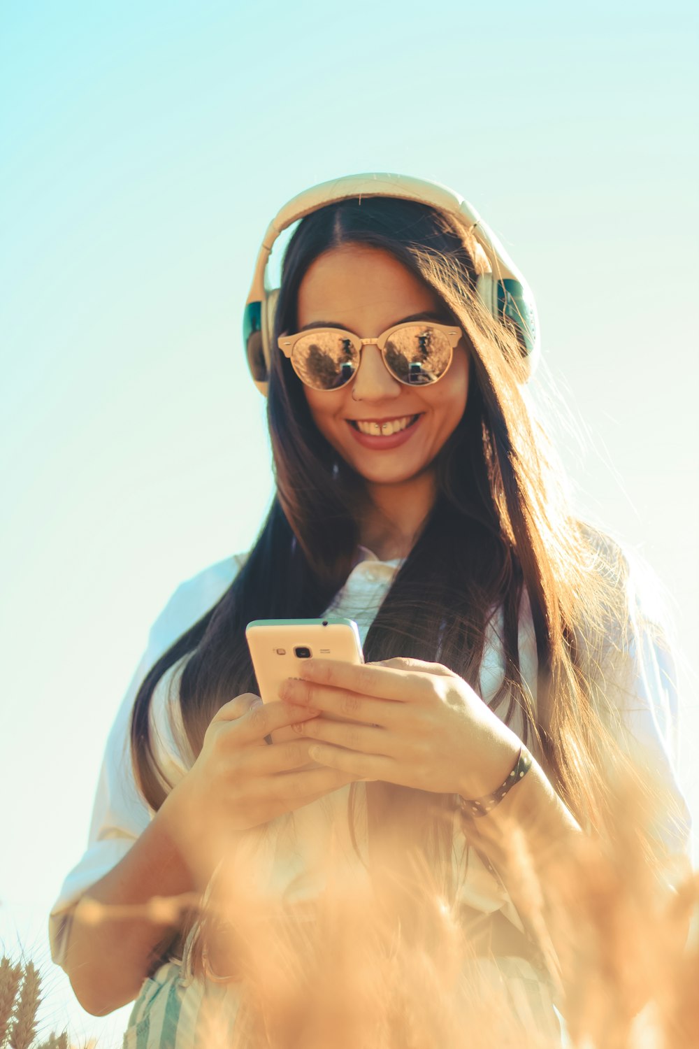 woman standing and smiling while using phone