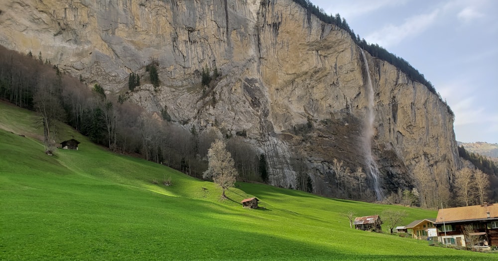 houses on grass field near rock mountain during day