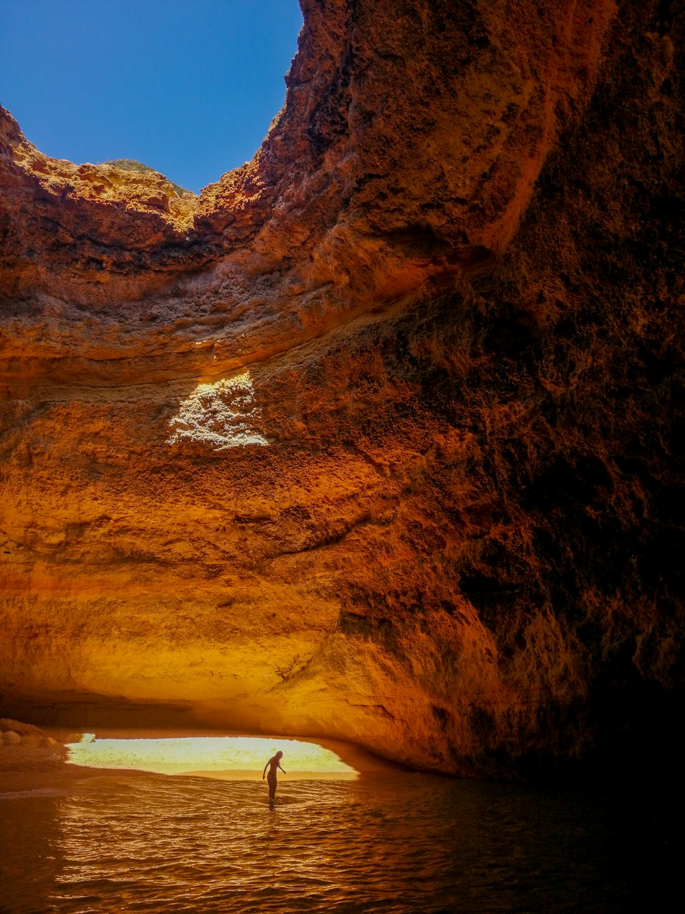 man inside rock formation with body of water