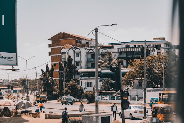 A lively street scene with colorful tuk-tuks and bustling market stalls under bright sunshine.