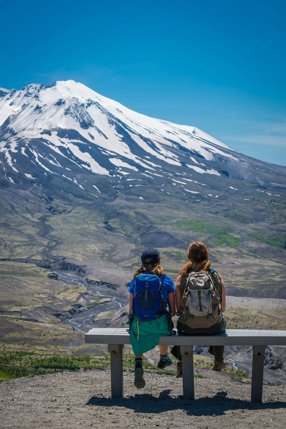 two people sitting on bench facing mountain