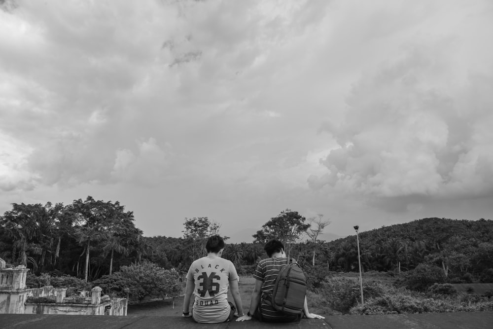 grayscale photo of two men sitting on roof