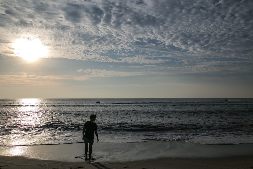 man walking at the beach under cloudy sky