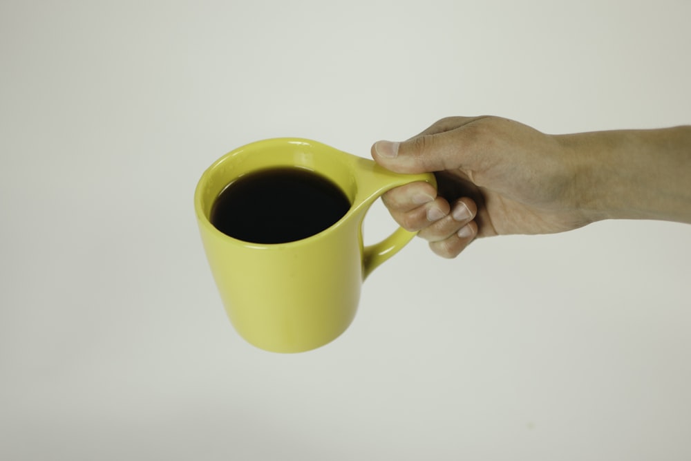 person holding cup of black coffee