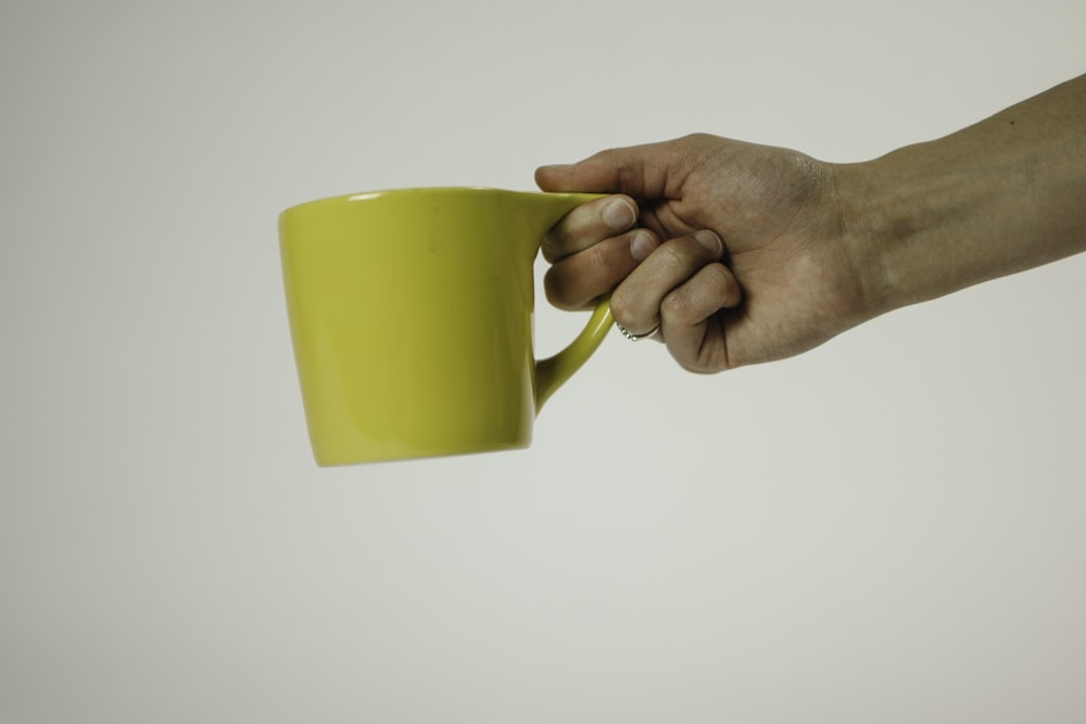 person holding yellow mug