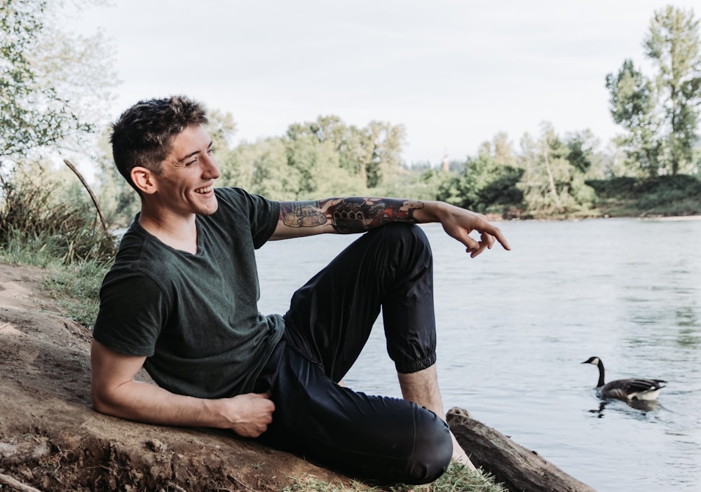 man sits near lake