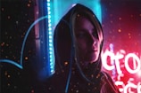 Close-up of a black hoodie with electric blue accents under neon city lights.