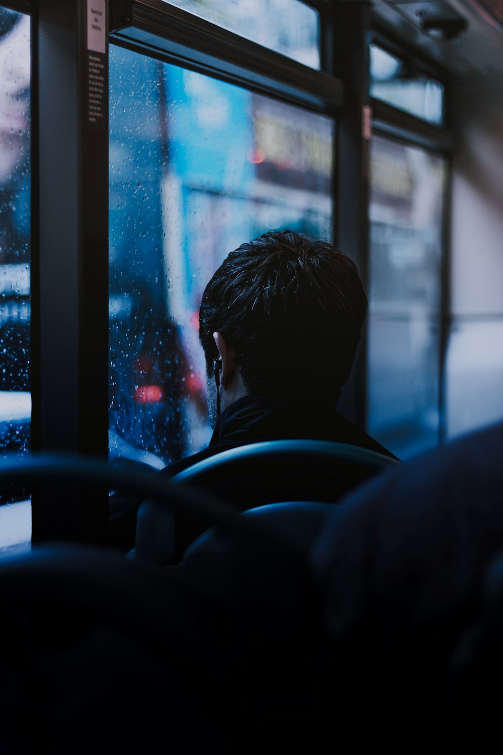 man sitting on black vehicle seat next to window panel