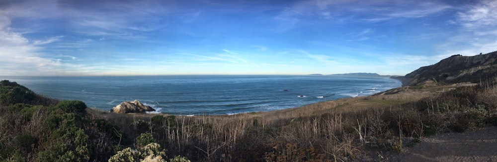 photographie de bord de mer à côté de la montagne pendant la journée