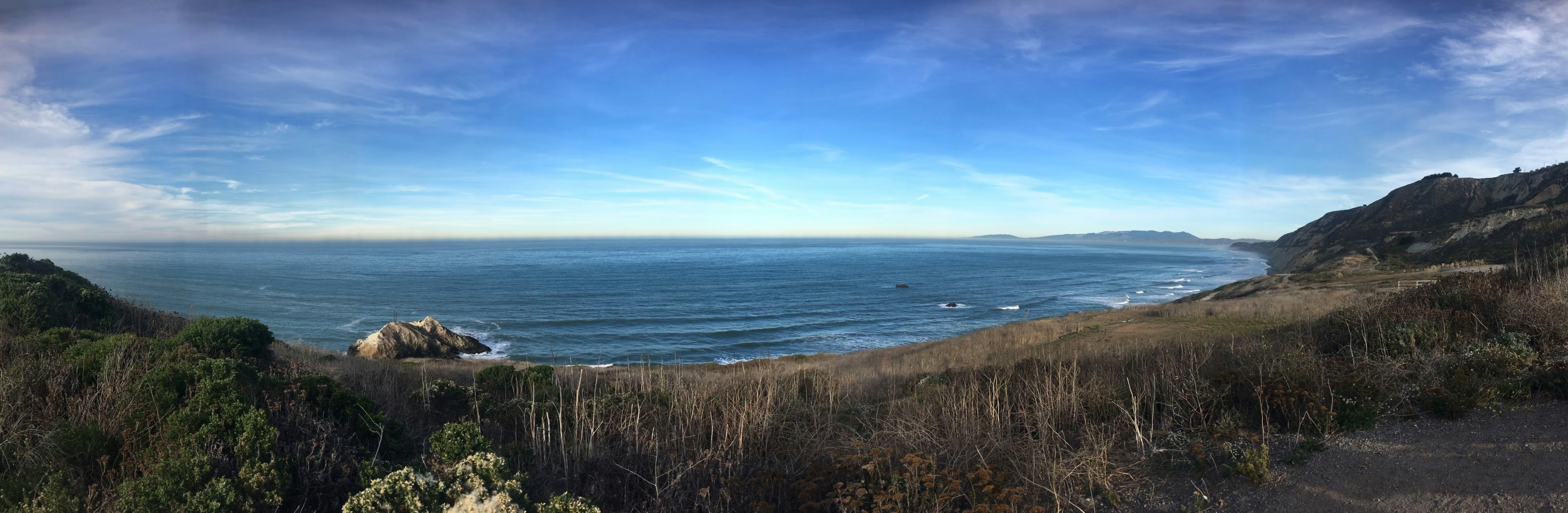 photography of seashore beside mountain during daytime