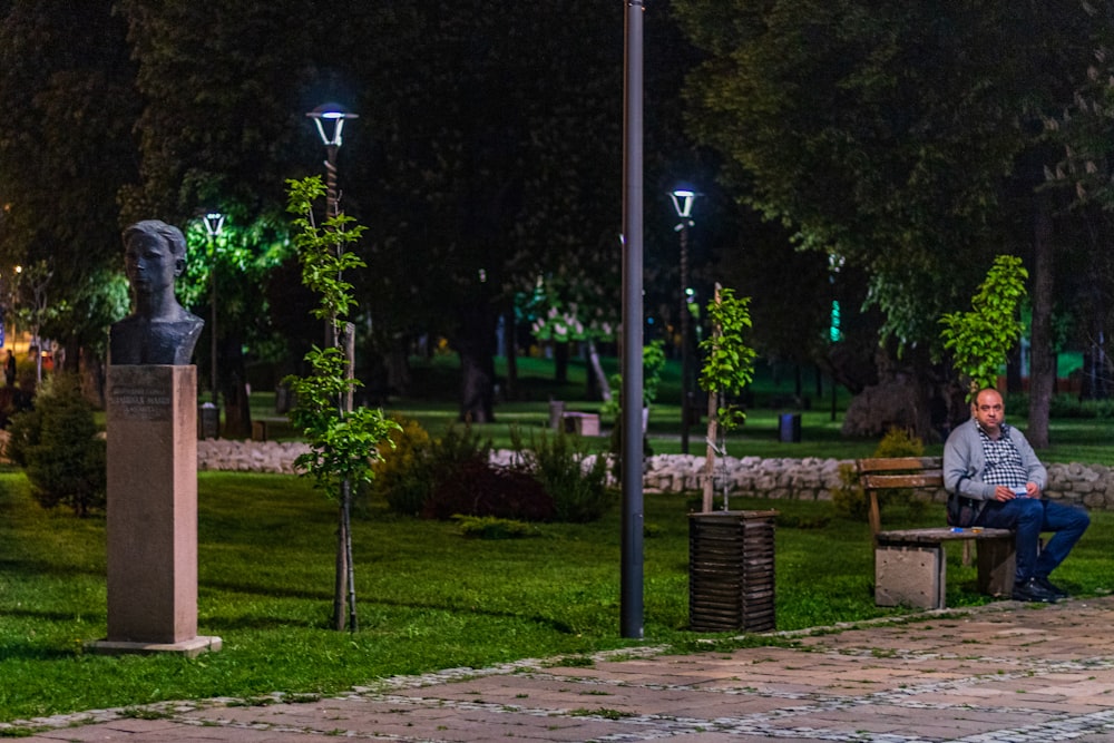 man sitting on bench on park during nighttime