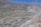 A large open-pit mine with terraced levels carved into a hillside, creating a massive and layered appearance. The landscape is mostly barren with dusty roads leading to various levels of the pit. The scene is devoid of vegetation, emphasizing the stark industrial activity.