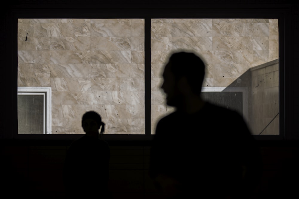 silhouette of man standing beside window