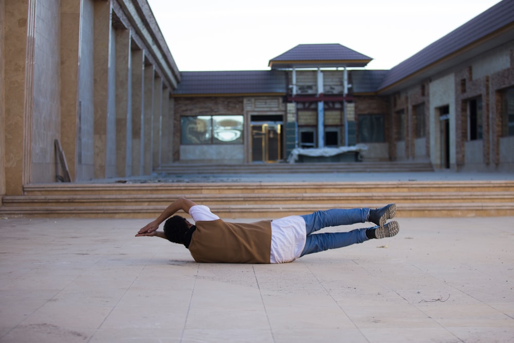 man lying in front of white and brown building