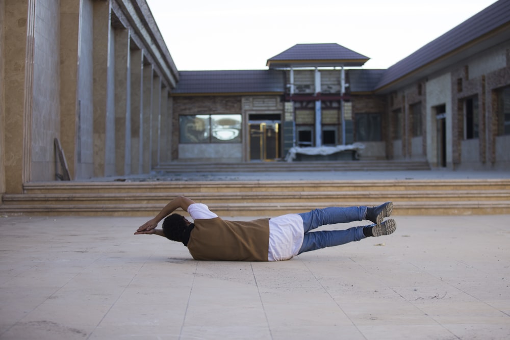 man lying in front of white and brown building