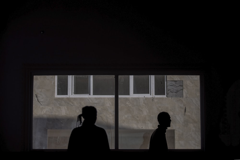 a couple of people standing in front of a window