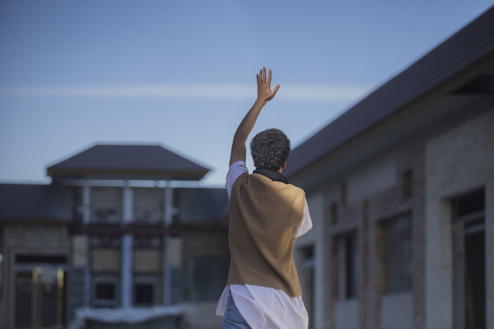 man standing and raising left hand during daytime