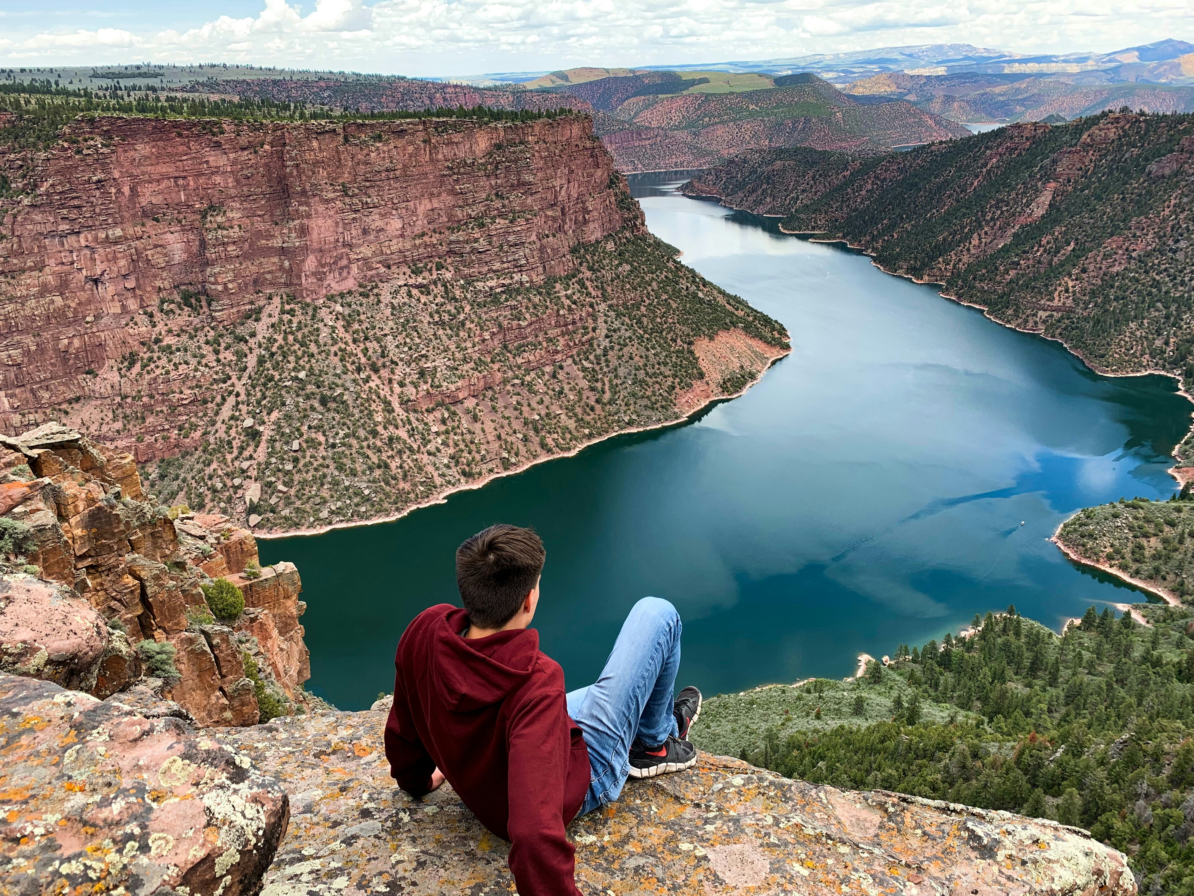 man sitting on cliff during daytime