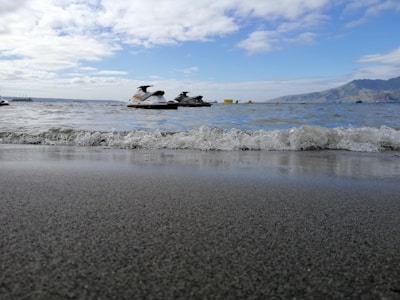 A jetski tour group cruising near the rocky coastline, waves gently splashing.
