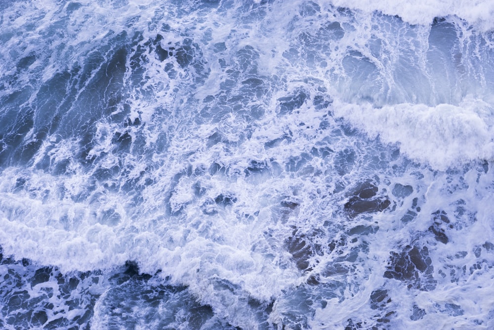 an aerial view of the ocean waves and rocks