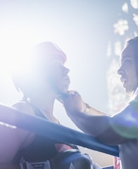 person fixing person's boxing headgear in the ring