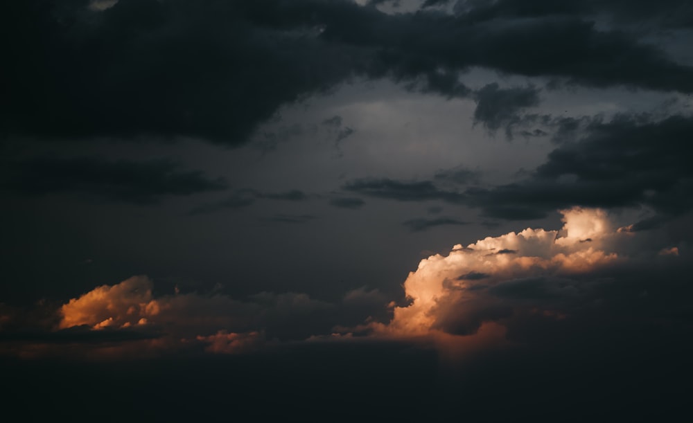 a plane flying through a cloudy sky at sunset